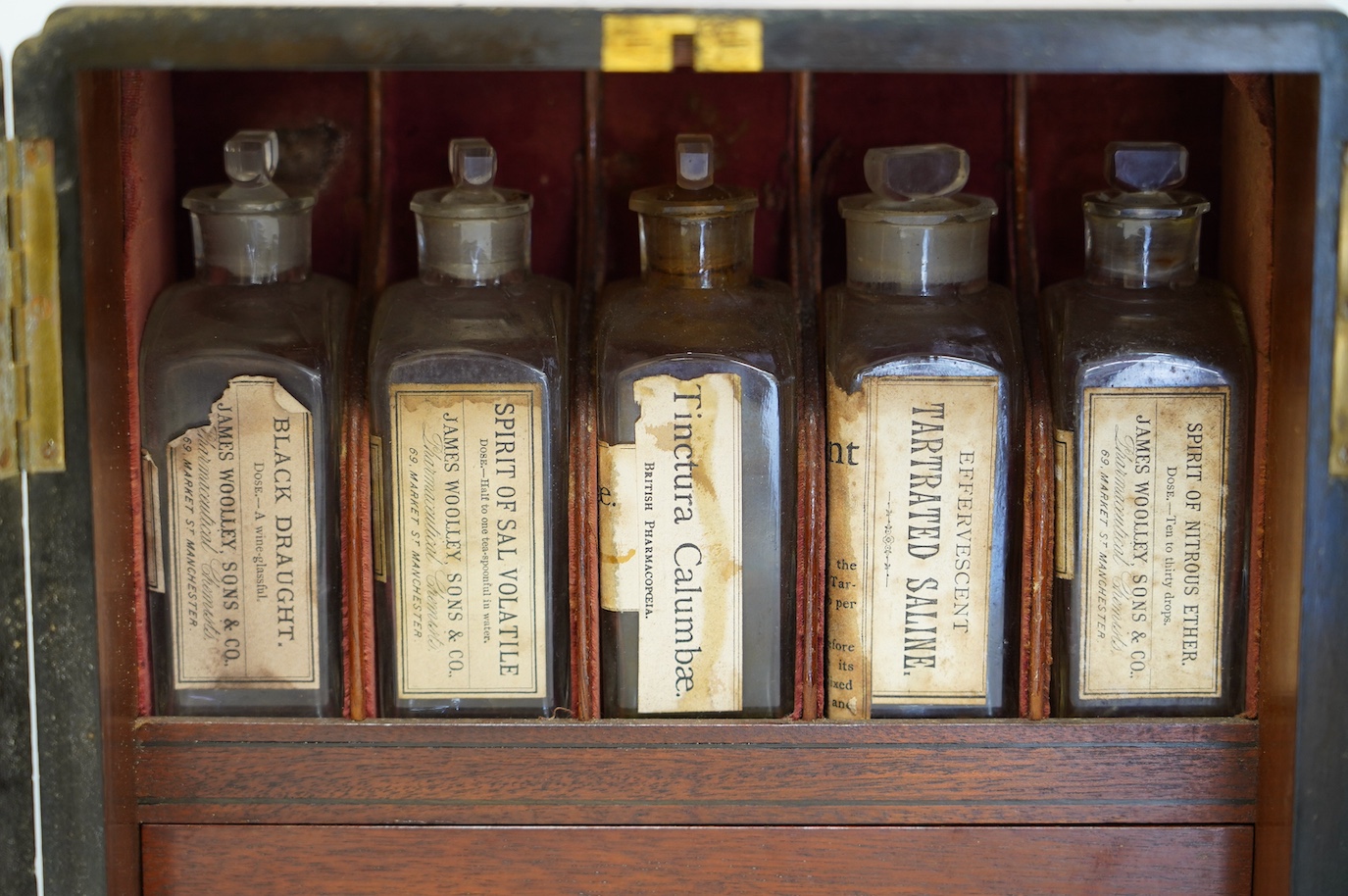 A late Victorian mahogany apothecary chest, containing a number of labelled glass bottles with preparations by James Woolley Sons and Co, Pharmaceutical Chemists, 28.5cm high, 25.5cm wide, 21cm deep. Condition - poor to